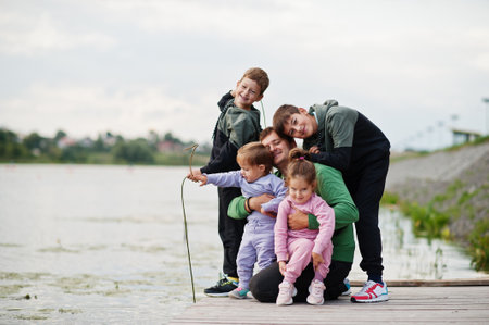 father love. Dad with four kids outdoors on the pier. Sports large family spend free time outdoors.