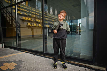 Boy with penny board in hands at stadium.