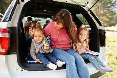 Family at vehicle interior. mother with her daughters. children in trunk. Traveling by car in the mountains, atmosphere concept.の写真素材