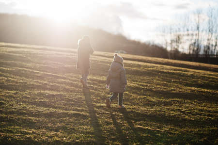 Young boy wear jacket and hat with sister in early spring forest.の写真素材