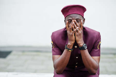Pain of war. Portrait of African American military man in red uniform and beret covers his face with...