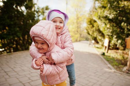 Two happy sisters hugging together outdoor.の写真素材