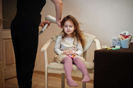Mom with dauhter making everyday routine together. Mother is brushing and drying child hair after shower.の写真素材