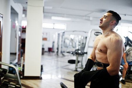 Muscular arab man training in modern gym. Fitness arabian men with naked torso doing exercises.の写真素材