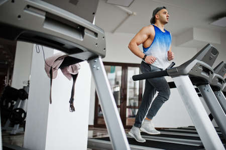 Fit and muscular arabian man running on treadmill in gym.の写真素材
