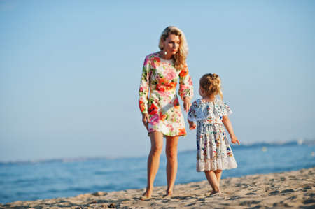 Mother and beautiful daughter having fun on the beach. Portrait of happy woman with cute little girl on vacation.の写真素材