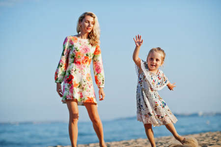 Mother and beautiful daughter having fun on the beach. Portrait of happy woman with cute little girl on vacation.の写真素材