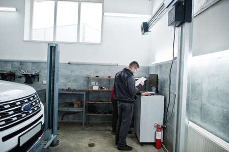 American SUV car on stand for wheels alignment camber check in workshop of service station.の写真素材