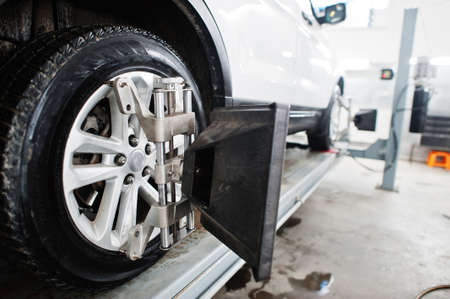 American SUV car on stand for wheels alignment camber check in workshop of service station.