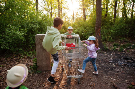 Kids with trolley having fun in forest.