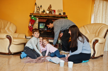Happy young large family at home by a fireplace in warm living room on winter day.の写真素材