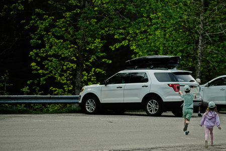 Kids running to car in parking at Austrian alps.
