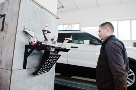 Auto mechanic sets american SUV car for diagnostics and configuration camber check in workshop of service station..の写真素材