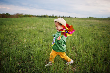 Babay girl with pinwheel at meadow.の写真素材
