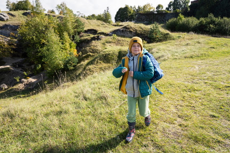 Activity on sunny autumn day, boy exploring nature. Kid wear yellow hat and backpack hiking.の写真素材