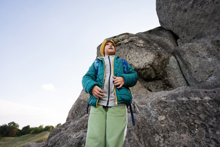 Boy with backpack climbing big stone in hill. Pidkamin, Ukraine.の写真素材