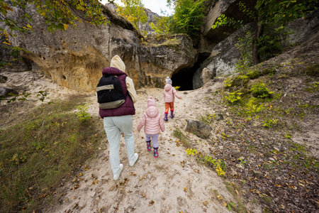 Mother with two daughters explore limestone stone cave at mountain in Pidkamin, Ukraine.の写真素材