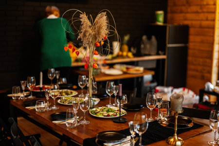 Large, long, decorated, wooden table and chairs, covered with dishes, flowers, candles.の写真素材