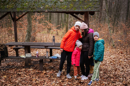 Mother with her kids having rest in autumn forest with roof shelter and picnic table.の写真素材