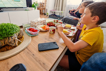Kids eating at home and watching tv.の写真素材