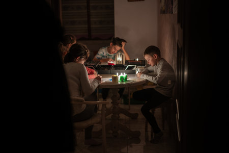 Family spending time together during an energy crisis in Europe causing blackouts. Kids drawing in...