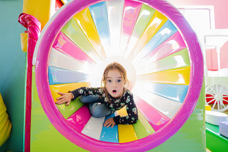 Funny girl playing at indoor play center playground in colored tube.の写真素材