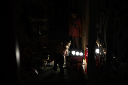 Sisters playing at home during a blackout using alternative lighting with solar panel.の写真素材