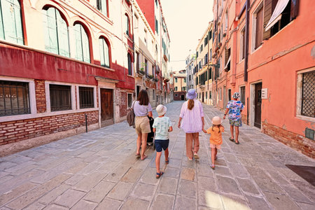 Back of family tourists walk in Ramo De La Piscina street, Venice, Italy.の写真素材