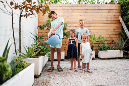 Children with can watering the flowers on the terrace of the house.