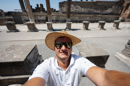 Man tourist in hat and sunglasses making selfie at Pompeii ancient city, Italy.