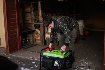Man wear in military jacket with gasoline portable mobile backup standby generator.の写真素材