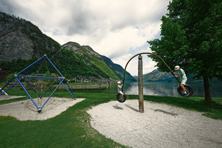 Two brothers ride on a swing from car tires at Hallstatt, Austria.の写真素材