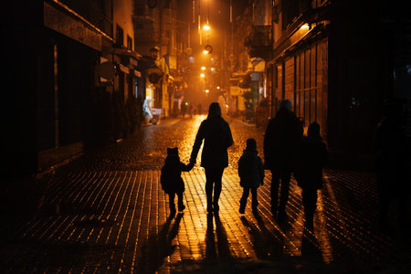 Back of silhouettes family walking in night city.