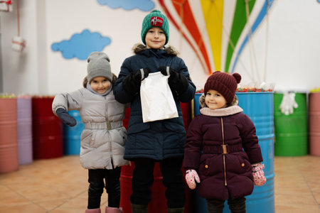 Happy little kids in a candy store chooses sweets, marmalade candies, puts them in a paper bag.の写真素材