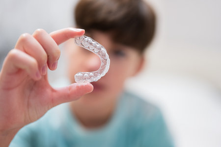 Teenager boy wear simulator orthodontic silicone invisible leveling braces for teeth.  Dental...
