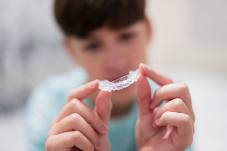 Teenager boy wear simulator orthodontic silicone invisible leveling braces for teeth.  Dental...