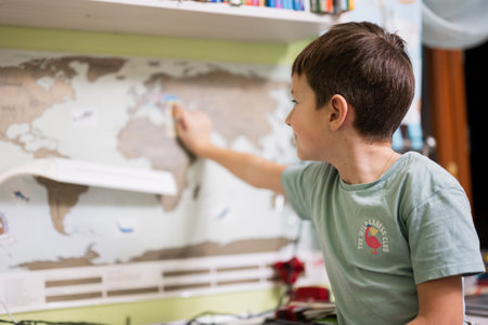 Boy shows Ukraine with his finger on the world map in children's room.の写真素材