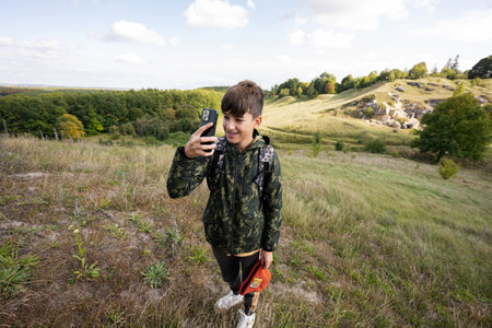 Activity on sunny autumn day, boy exploring nature. Kid wear backpack hiking and making photo on...