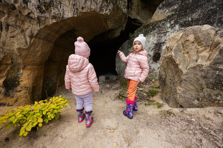 Two girls kids explore limestone stone cave at mountain in Pidkamin, Ukraine.の写真素材