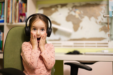 Young girl wearing headphones, enjoys her remote education. Distant studying, homeschooling. Funny...