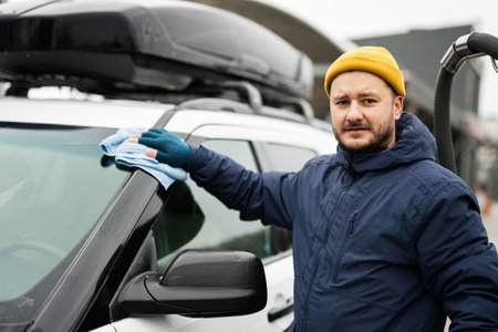 Man wipes american SUV car with a microfiber cloth after washing in cold weather.の写真素材