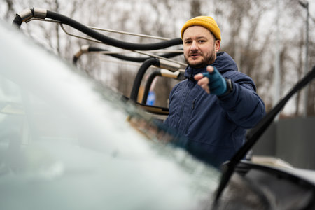 Man wipes american SUV car windshield with a microfiber cloth after washing in cold weather.の写真素材