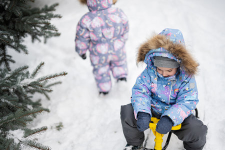 Children play outdoors in snow. Two little sisters enjoy a sleigh ride. Child sledding. Toddler kid...