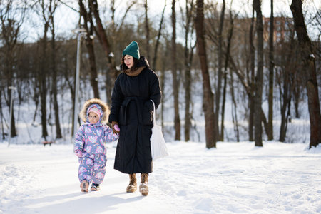 Mother and child walking on a sunny frosty winter day in the park.の写真素材