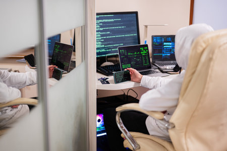 Boy hacker fraudulently use credit card for payment. Internet theft . Man wearing a balaclava and...