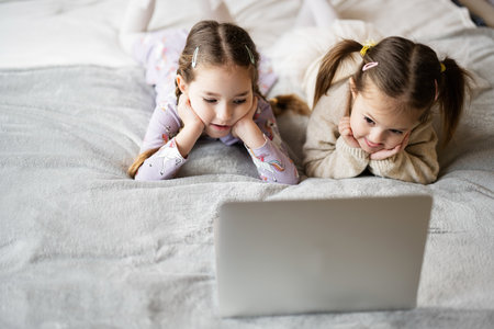 Two girls sisters watching on laptop. Technology and home concept.の写真素材