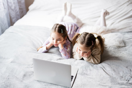 Two girls sisters watching on laptop. Technology and home concept.の写真素材