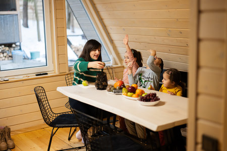 Mother with three children eat fruits in wooden country house on weekend.の写真素材