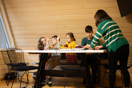 Mother with four children eat fruits in wooden country house on weekend.の写真素材