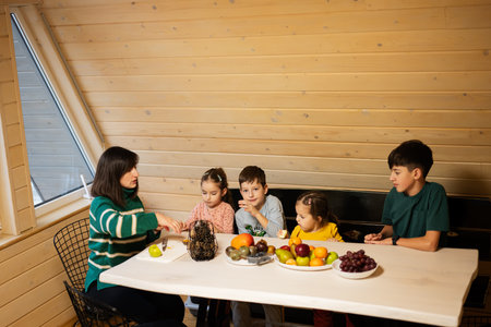 Mother with four children eat fruits in wooden country house on weekend.の写真素材